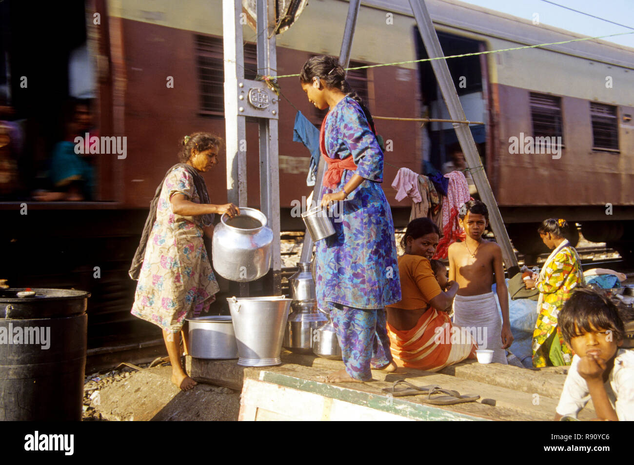 Slum vicino alla ferrovia, donne che raccolgono acqua, linea portuale, bombay, mumbai, Maharashtra, India, asia Foto Stock