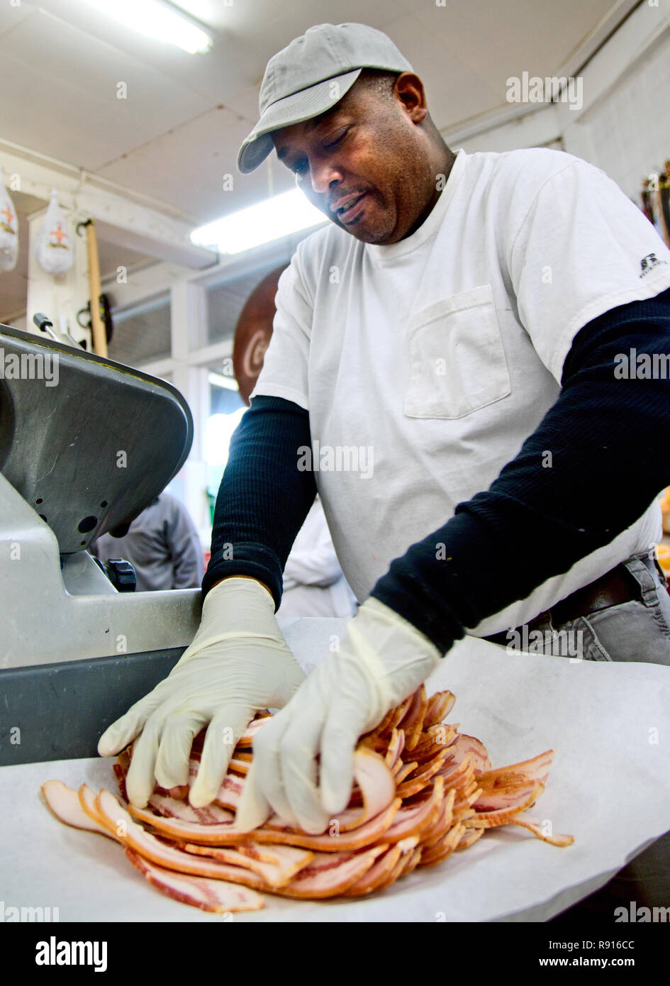 Frank Moore strati fette di pancetta, la preparazione di un pacchetto per un cliente, a Williams Brothers General Store di Philadelphia, Mississippi. Foto Stock