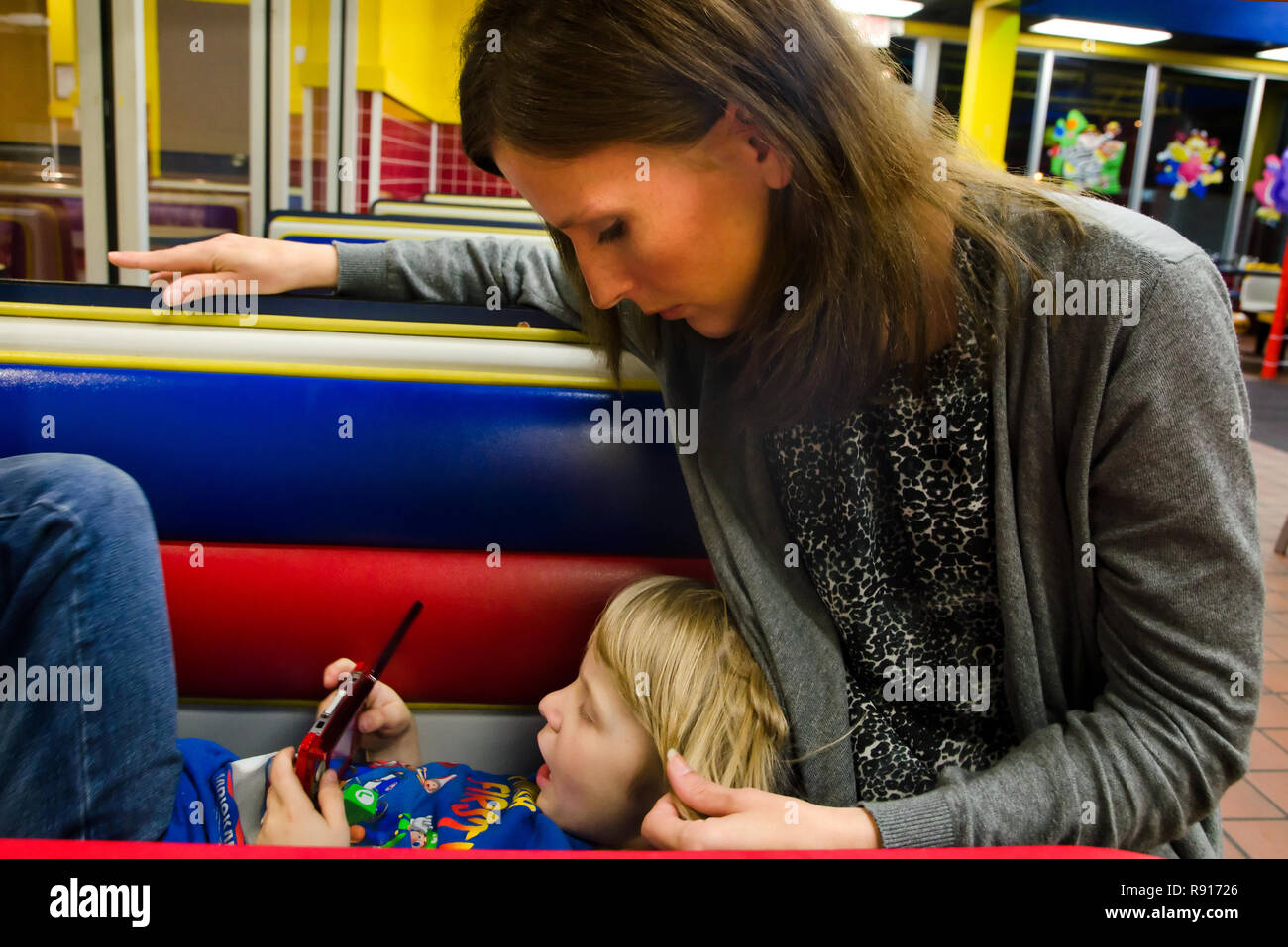 Un ragazzo che ha la Sindrome di Asperger, una forma di autismo, riproduce un video gioco come sua madre tratti i suoi capelli, 19 aprile 2012, in Columbus, Mississippi. Foto Stock