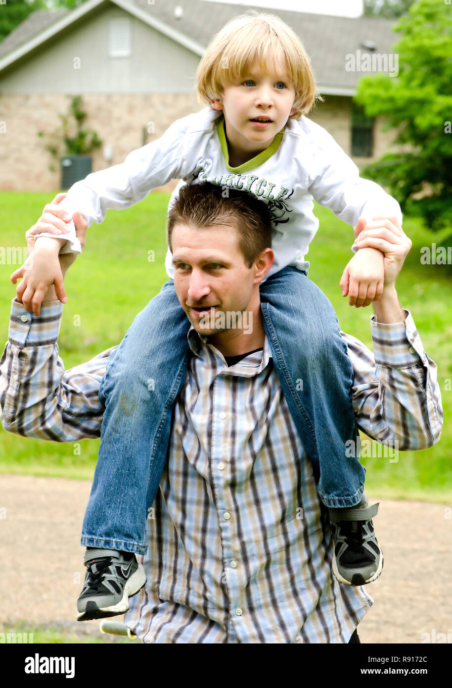 Un ragazzo autistico ottiene un piggyback ride da suo padre in una nuova speranza, Mississippi. Foto Stock