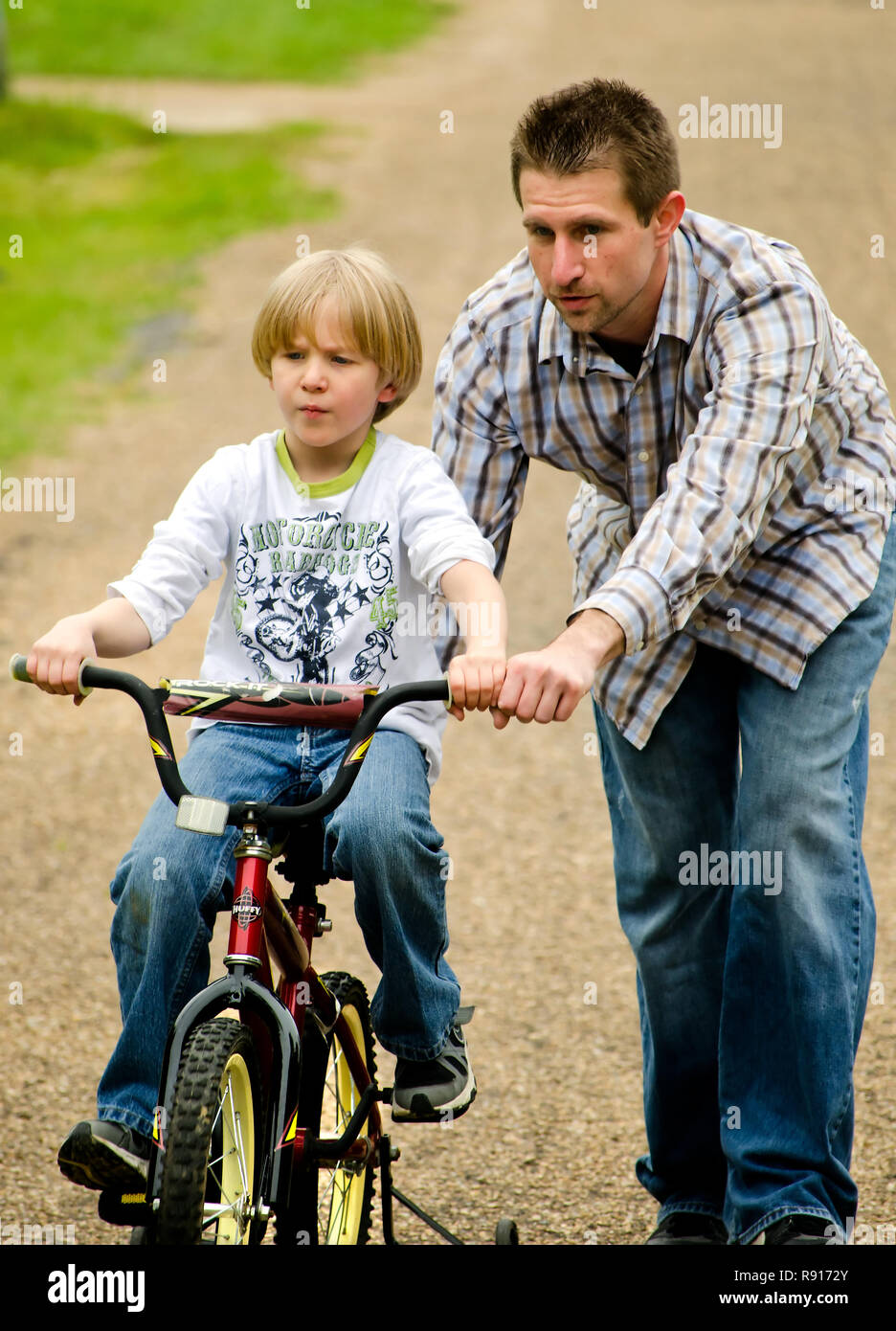 Un ragazzo autistico ottiene aiuto da suo padre come cavalca la sua bicicletta su una ripida collina, Aprile 21, 2012, nella nuova speranza, Mississippi. Foto Stock