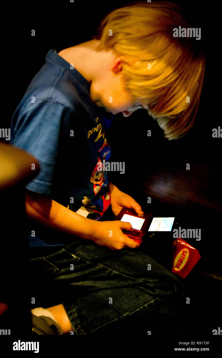 Un bambino gioca Super Mario sul suo Nintendo 3DS, 19 aprile 2012, al di sotto di un ristorante tavola in Columbus, Mississippi. Foto Stock