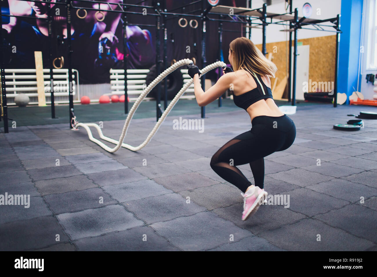 Donna forte esercizio con funi di battaglia presso la palestra. Atleta  facendo battaglia corda allenamento in palestra Foto stock - Alamy