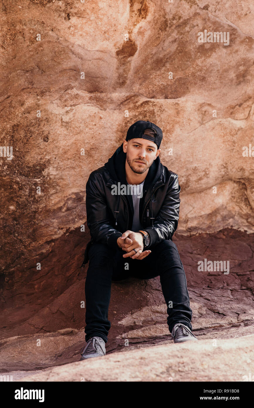 Ritratto di giovane Buona Cerchi viaggio Casual Uomo bello sorridente vicino al deserto di antiche rocce rosse in camicia al di fuori Foto Stock