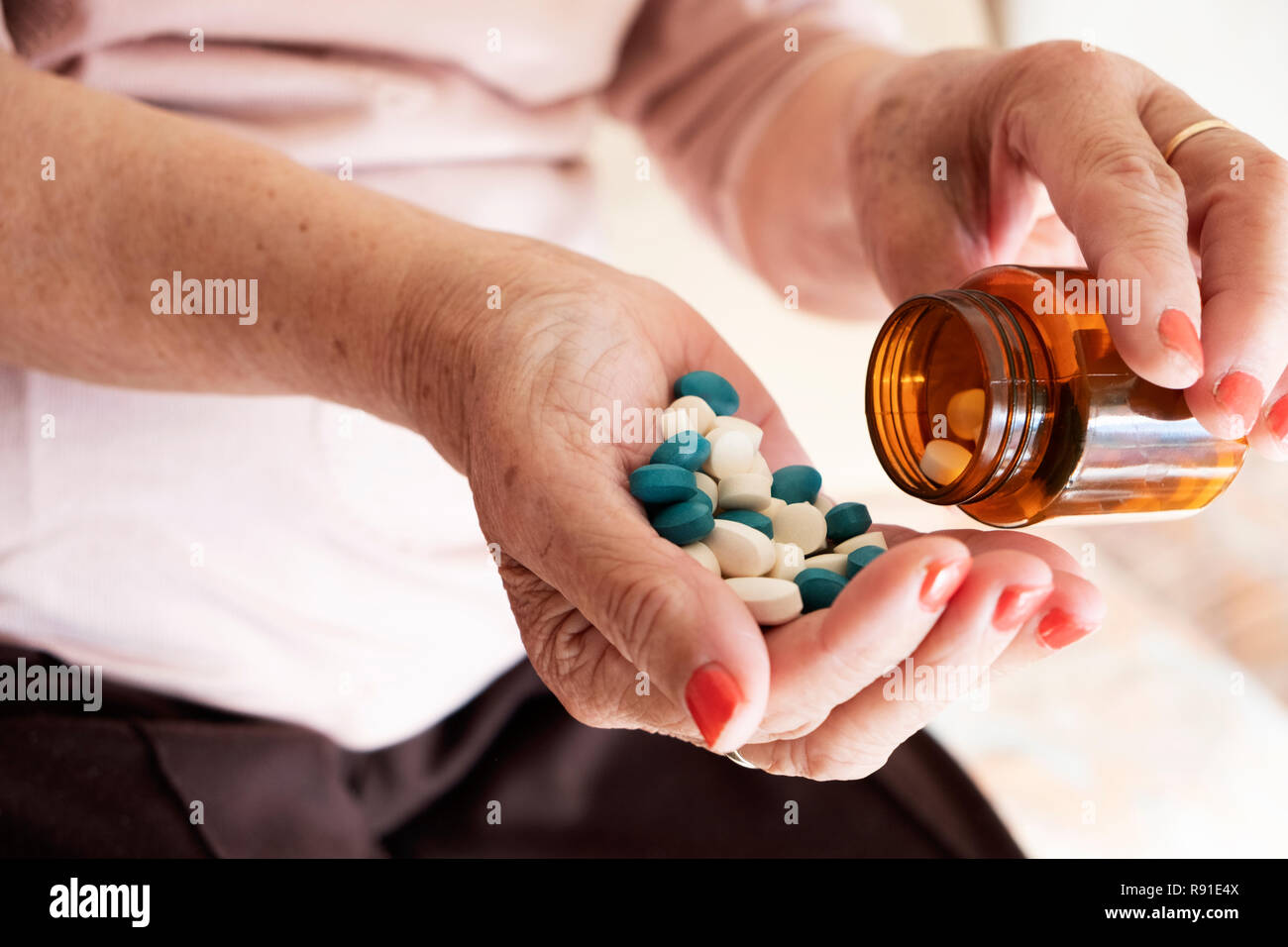 Primo piano di un senior donna caucasica con un mucchio di diverse pillole in mano Foto Stock