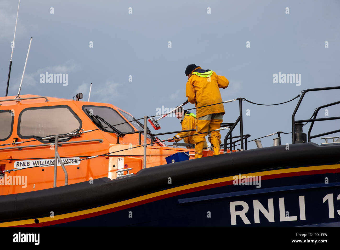 Due RNLI Membri di equipaggio per il lavaggio e la pulizia del Llandudno scialuppa di salvataggio William F Yates dopo gli esercizi di mare Foto Stock