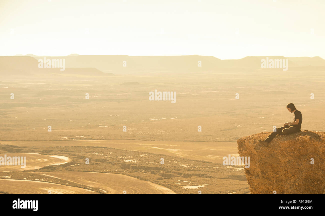 Uomo che guarda l'orizzonte al tramonto in Bardenas Reales desert, Navarra (Spagna) Foto Stock