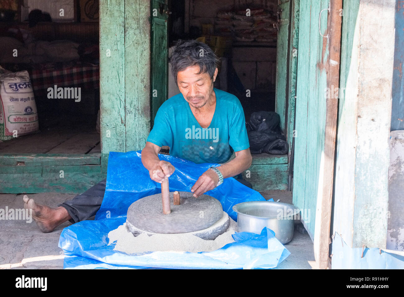 Uomo nepalese macinazione di farina con una mano macina azionata Foto Stock