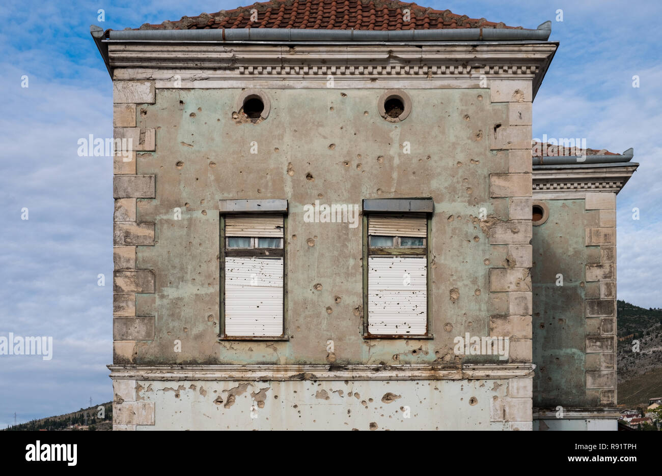 Edificio abbandonato di Mostar che mostra ancora segni della guerra bosniaca 20 anni più tardi con schegge e fori di proiettili sulla facciata sbiadito Foto Stock