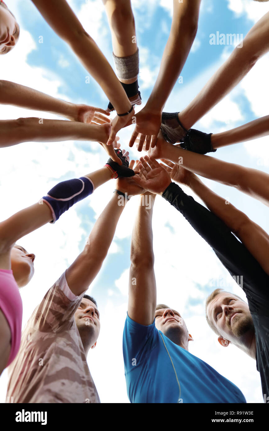 Vista dal basso delle persone le mani unite al centro del cerchio. Il lavoro di squadra, di cooperazione e di sostegno. Gli allenamenti sportivi di mattina. In esecuzione Foto Stock