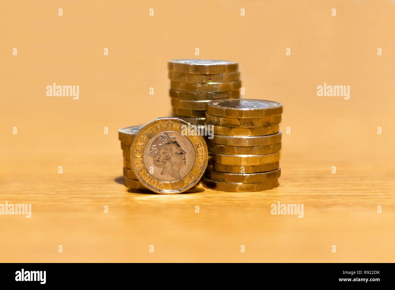Pile e cumuli di British GBP monete doro Moneta soldi su sfondo di legno con spazio vuoto Foto Stock