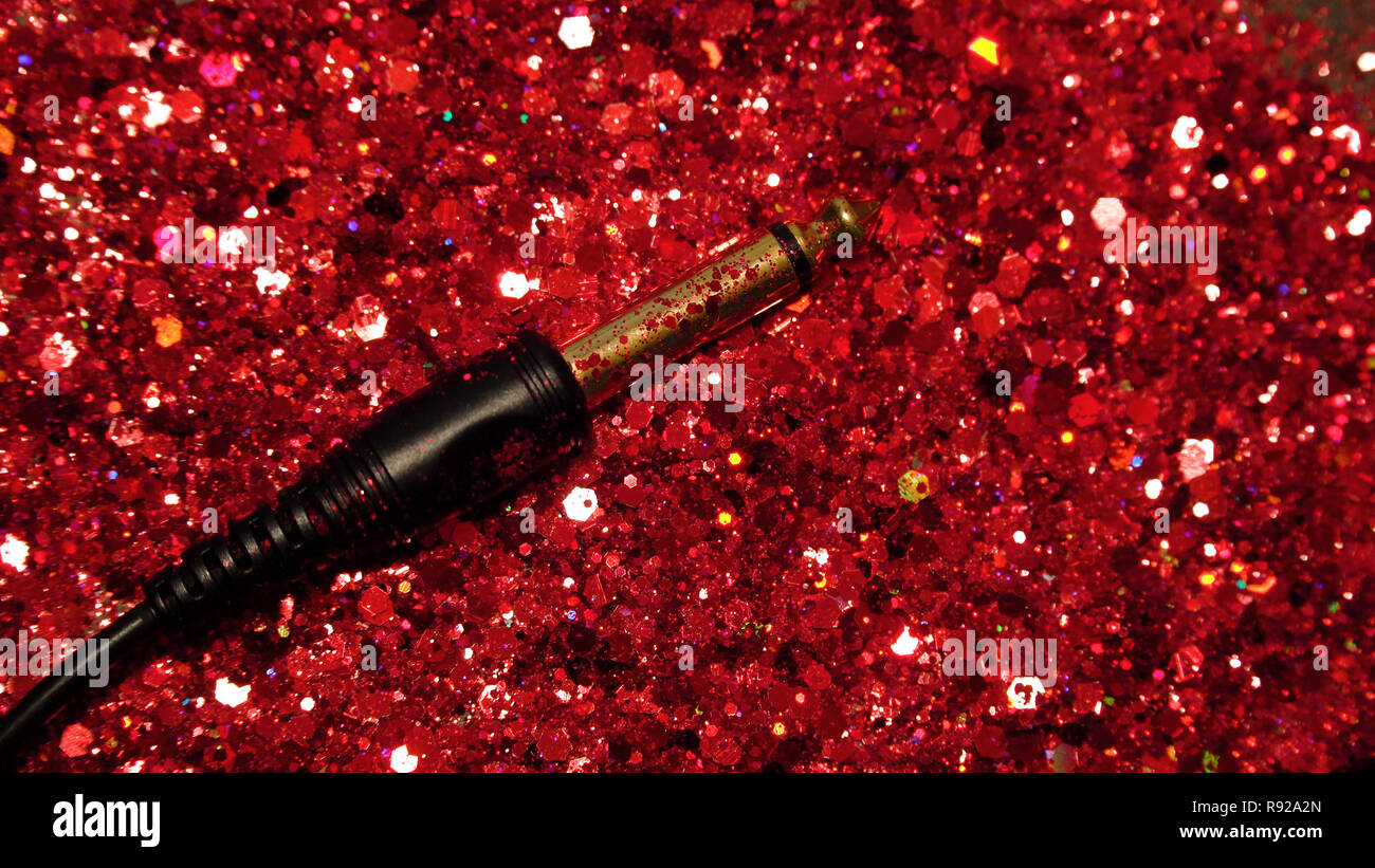 Il cavo nero su uno sfondo di colore rosso glitter Foto Stock