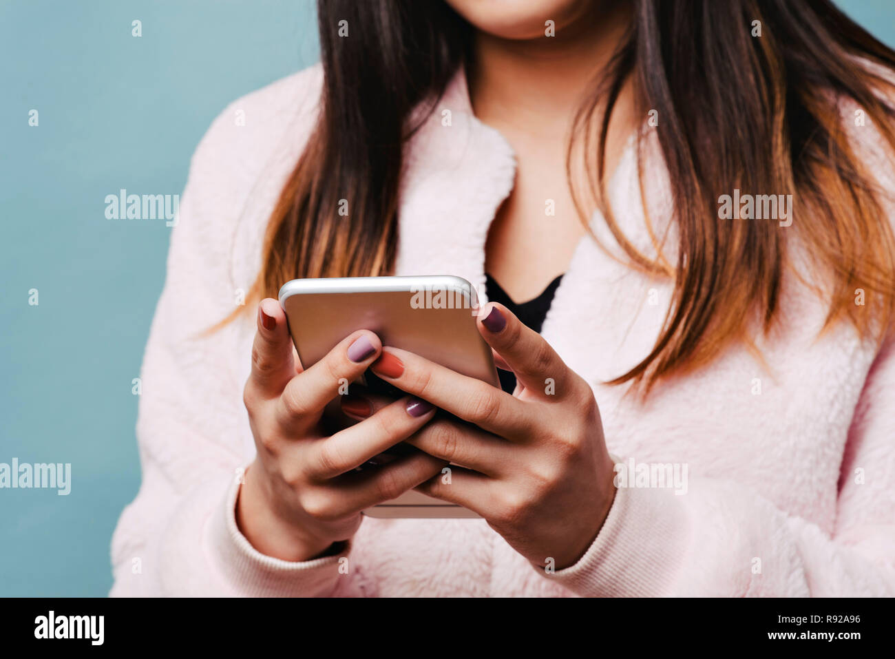 Young Teen femmina invia un testo con il suo smart phone con un cappotto alla moda Foto Stock