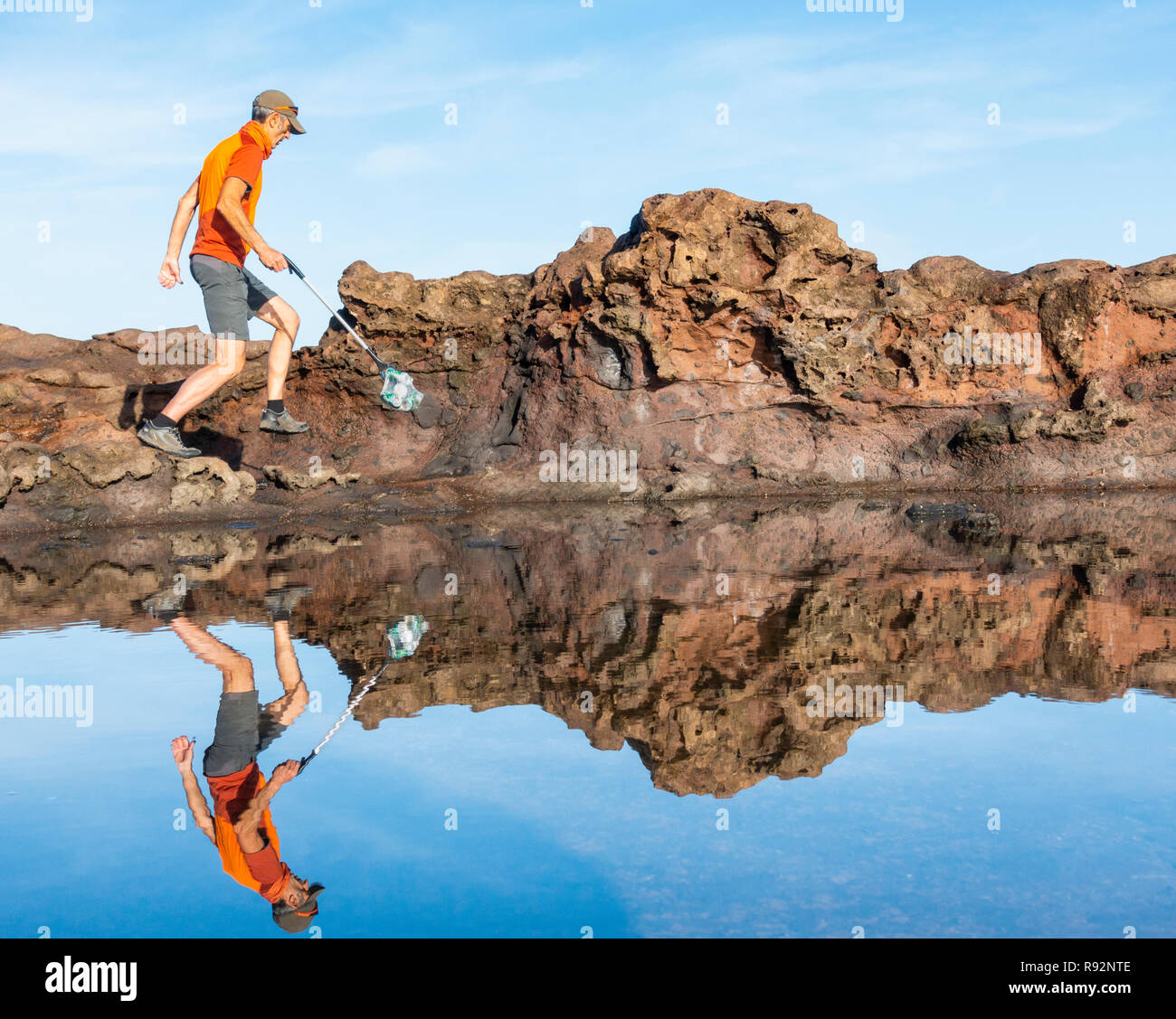 Un valore di Plogger/pareggiatore raccoglie rifiuti plastici dalla spiaggia durante la sua corsa mattutina Foto Stock