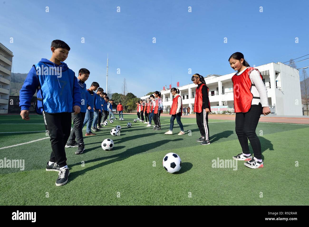 Xiema, Cina. Xix Dec, 2018. Gli studenti fanno pratica con le abilità di calcio in città Xiema Central School in Xiema township di Baokang County, centrale cinese della provincia di Hubei, Dic 18, 2018. Città Xiema Scuola centrale, un rurale Boarding School Situata nella remota area montuosa della provincia di Hubei, è il primo soccer-featured scuola pilota in Baokang. La scuola ha costruito un campo di calcio nel 2015, e aggiunto il calcio nel suo curriculum, fornendo agli studenti un accesso a più possibilità di giocare a calcio, nonché per aiutare i giovani calciatori inseguire i loro sogni. (Xinhua/Yang Tao) Credito: Xinhua/Alamy Live News Foto Stock