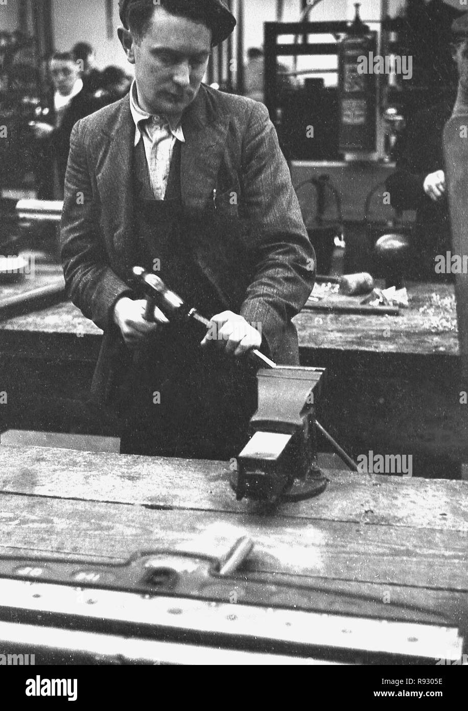 1940s, storico, all'interno di un workshop su un banco da lavoro, un disoccupato di minatore gallese apprendere una nuova abilità di lamiera, Merthyr, Galles. Foto Stock