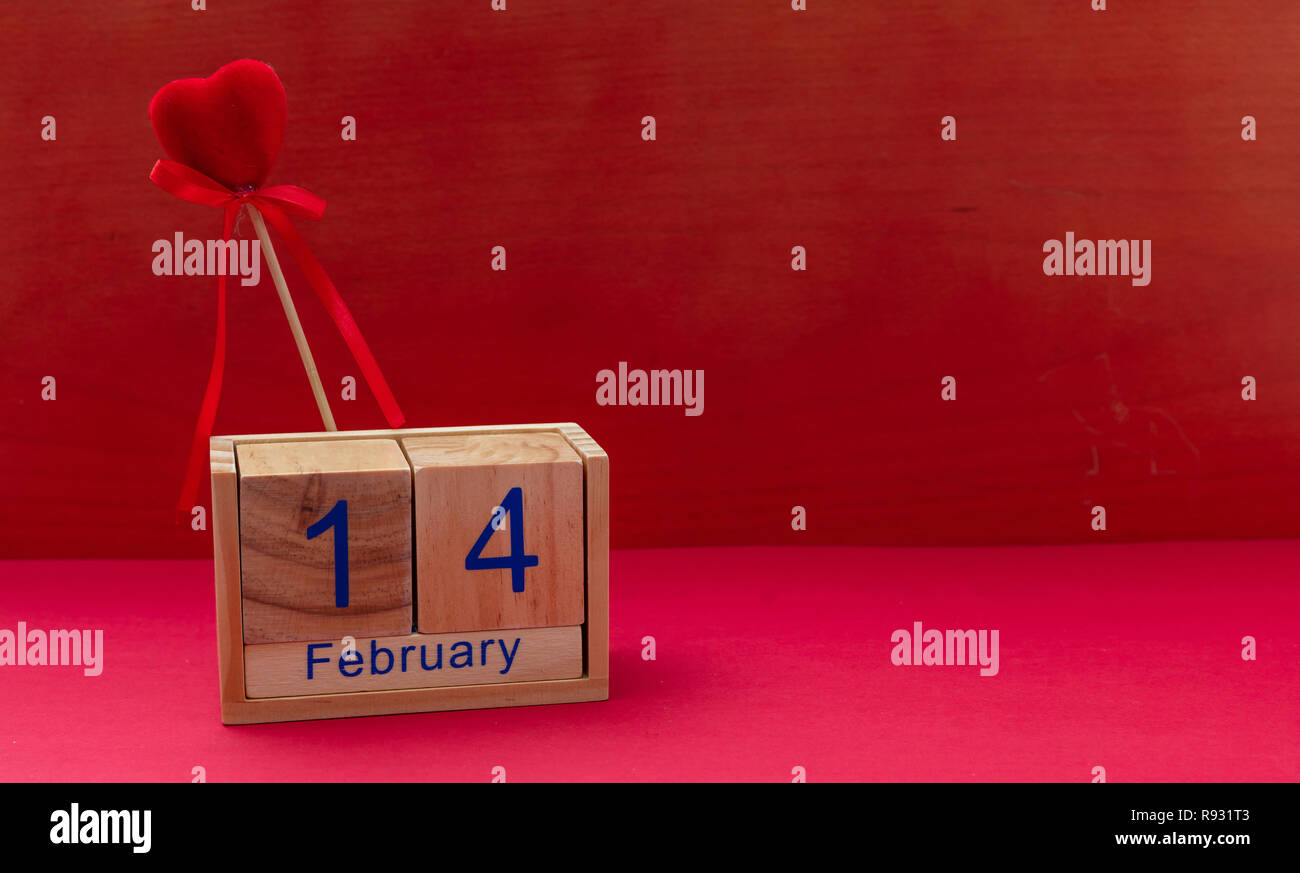 Il giorno di San Valentino. Calendario di cubi di legno con 14 febbraio testo e velluto rosso a cuore, contro lo sfondo di colore rosso, spazio di copia Foto Stock