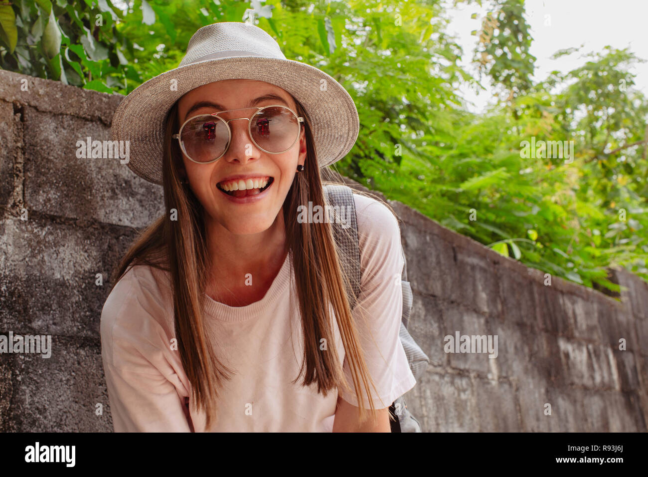 Attraente sorridente giovane donna in occhiali nei pressi di piante Foto Stock