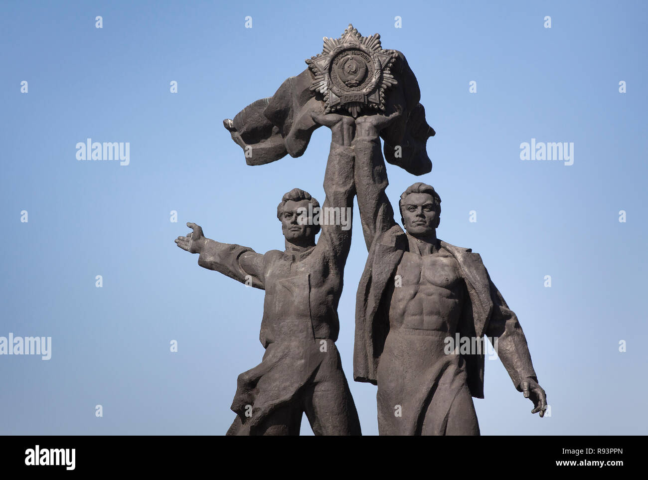 Statua di realismo Sovjet: due giovani uomini di pietra nera con in mano una CCCP medaglione, Kiev, Ucraina Foto Stock