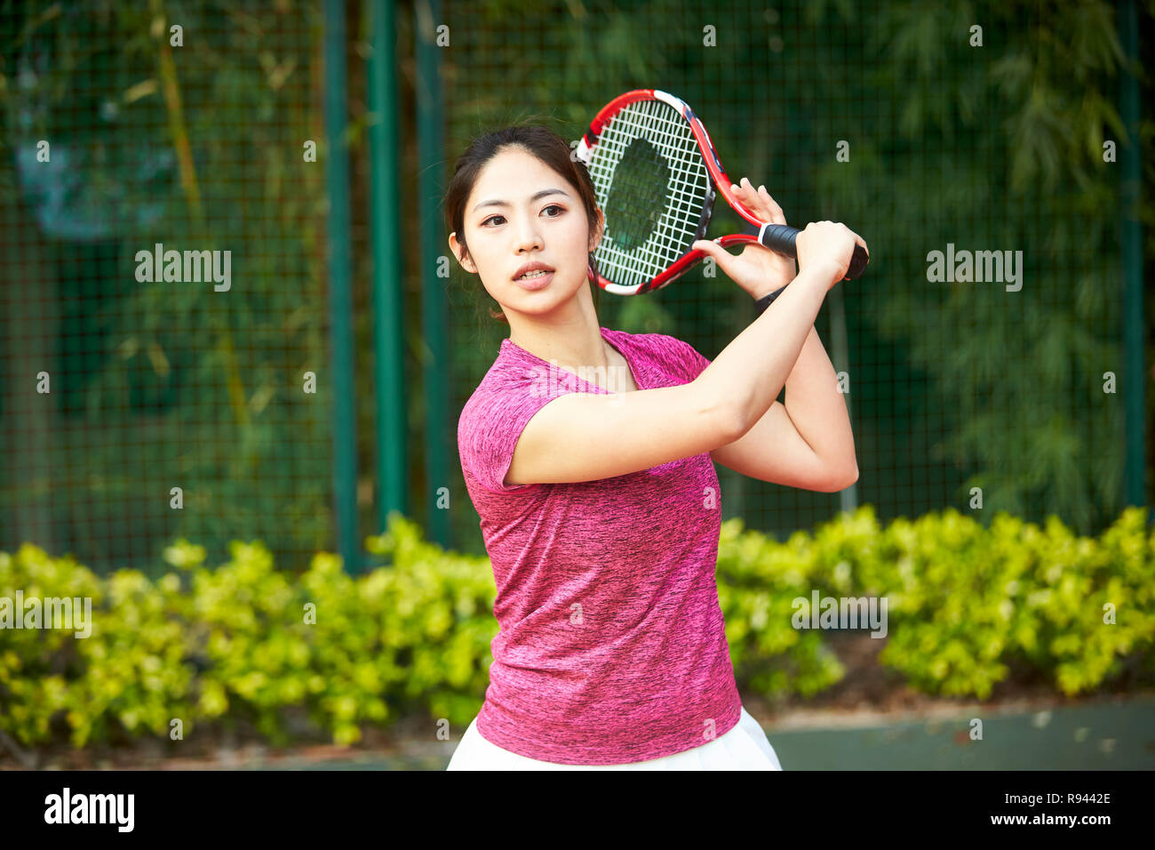Giovane donna asiatica femmina giocatore di tennis di colpire la palla con diretti Foto Stock