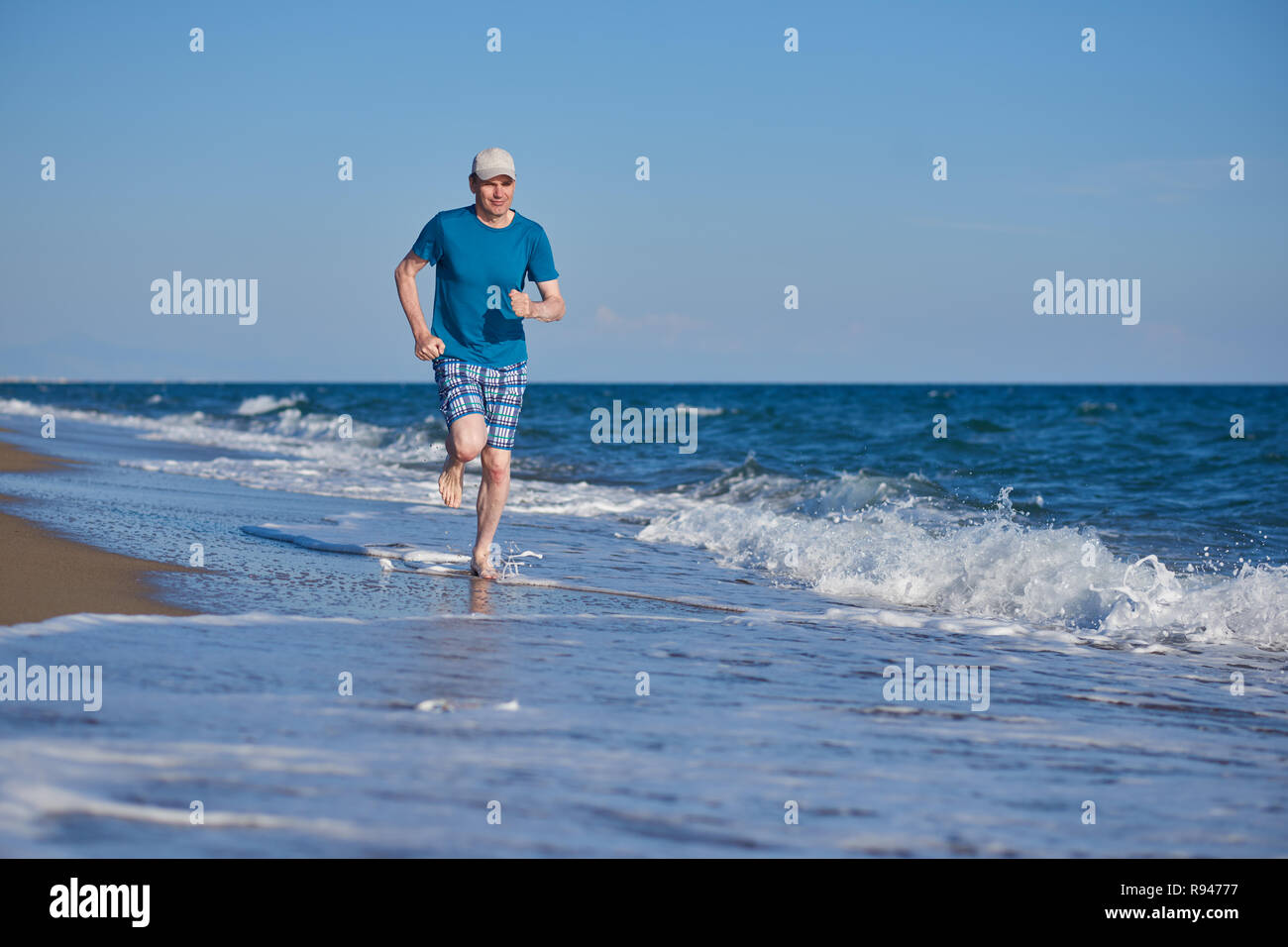 A piedi nudi uomo maturo durante il jogging sulla spiaggia Foto Stock