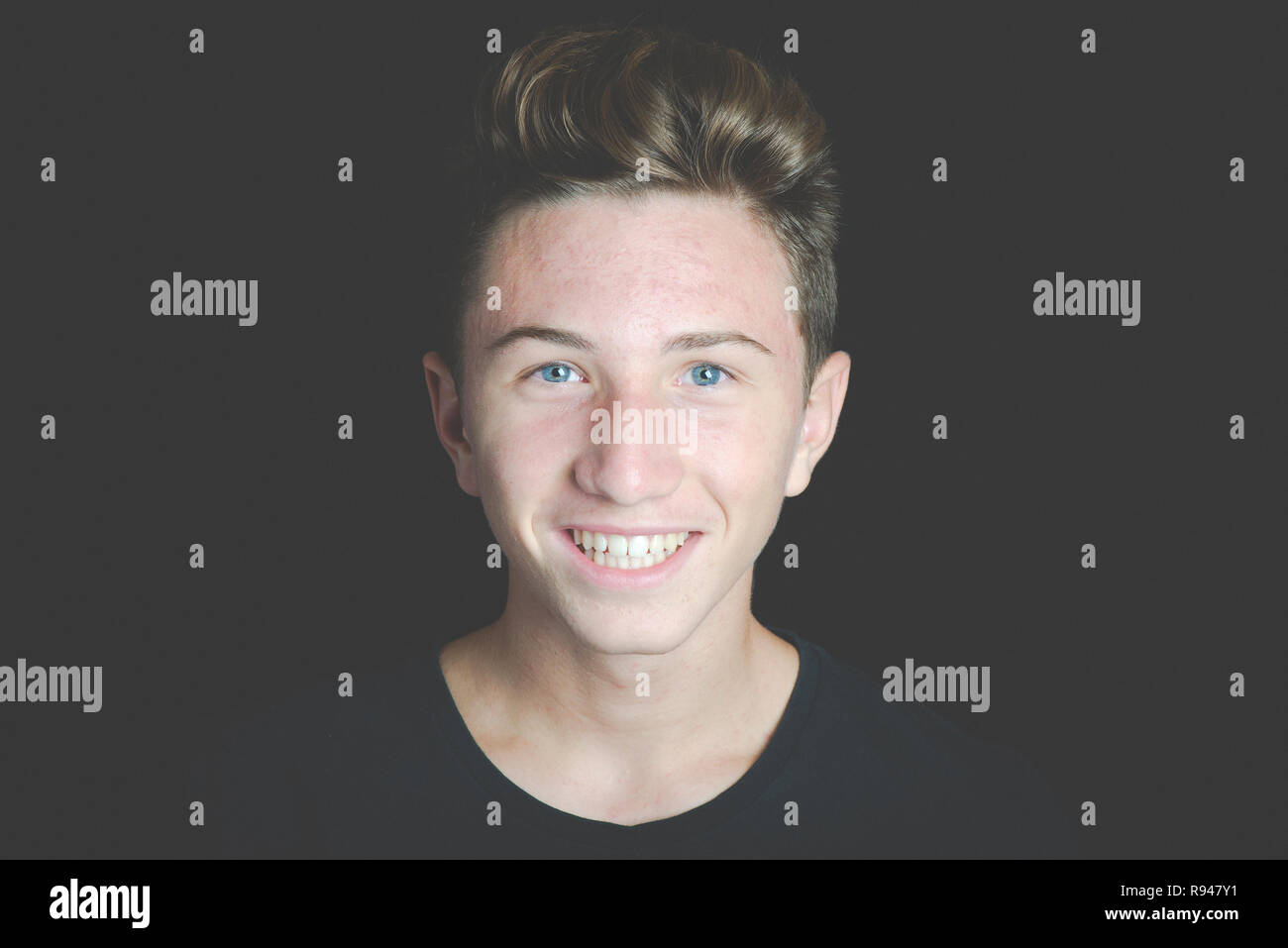 Giovane ragazzo sorridente ritratto su sfondo nero - Concetto di adolescenza senza problemi Foto Stock