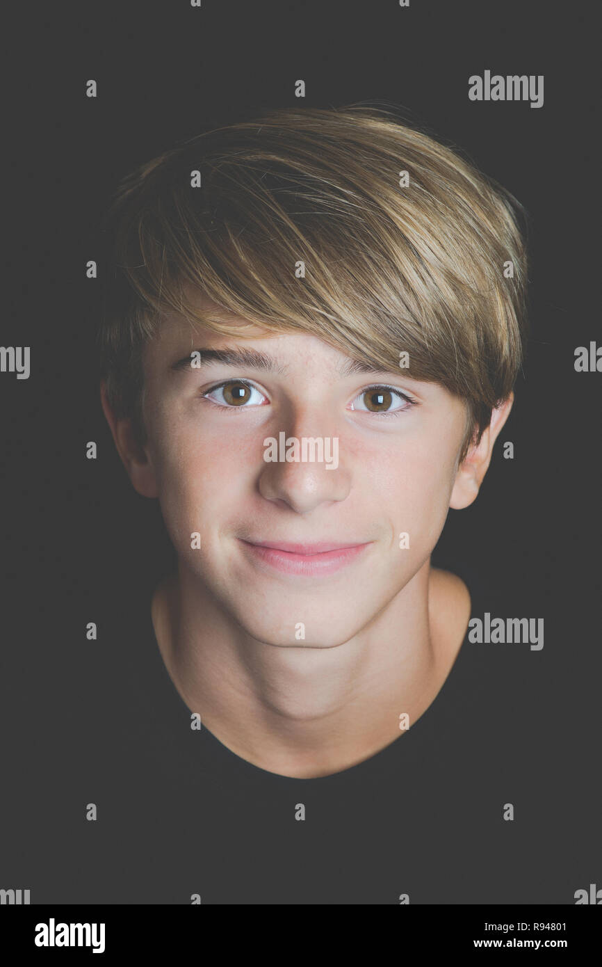 Giovane ragazzo sorridente ritratto su sfondo nero - Concetto di adolescenza senza problemi Foto Stock