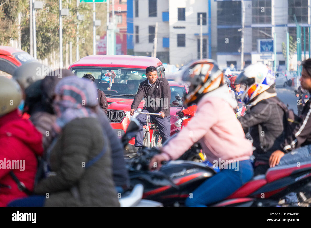 Ciclista in mezzo alla congestione del traffico per le strade di Kathmandu, Nepal la città capitale della Foto Stock