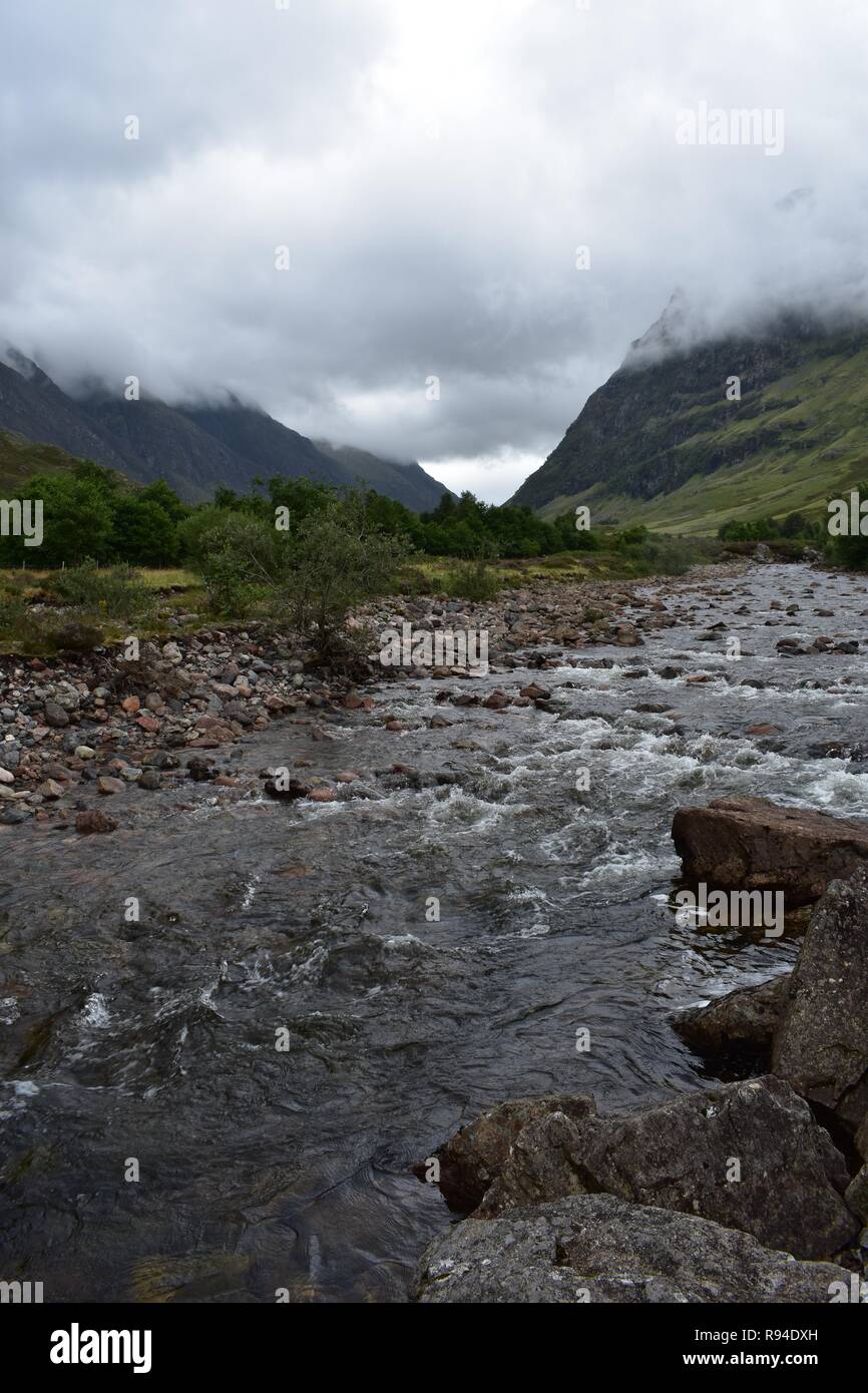 Il COE del fiume che scorre attraverso la valle di Glencoe Mountain Range nelle Highlands Scozzesi. Prese a piovere e Nuvoloso Giorno di agosto. Foto Stock