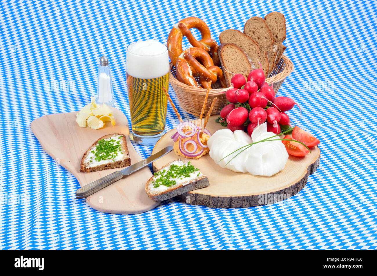 Snack bavarese con formaggio specialità chiamata 'obazda', servito con anelli di cipolla, salatini e ravanelli su un piatto di legno Foto Stock