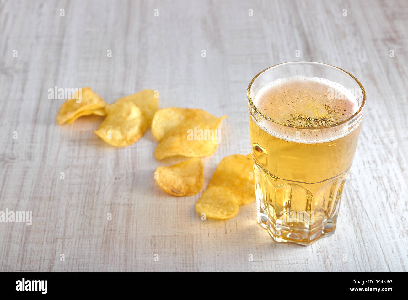 Un bicchiere di freddo, birra chiara con trucioli sparsi sul tavolo. copia spazio. La vista dalla cima del minimalismo. Foto Stock