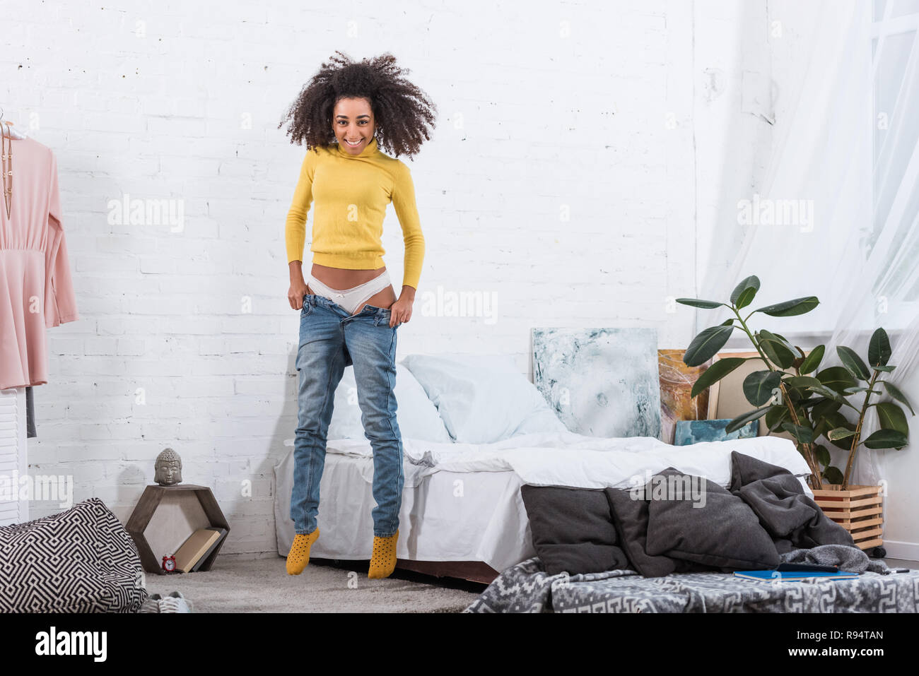 Pretty African American Girl mettendo in jeans in camera da letto a casa Foto Stock