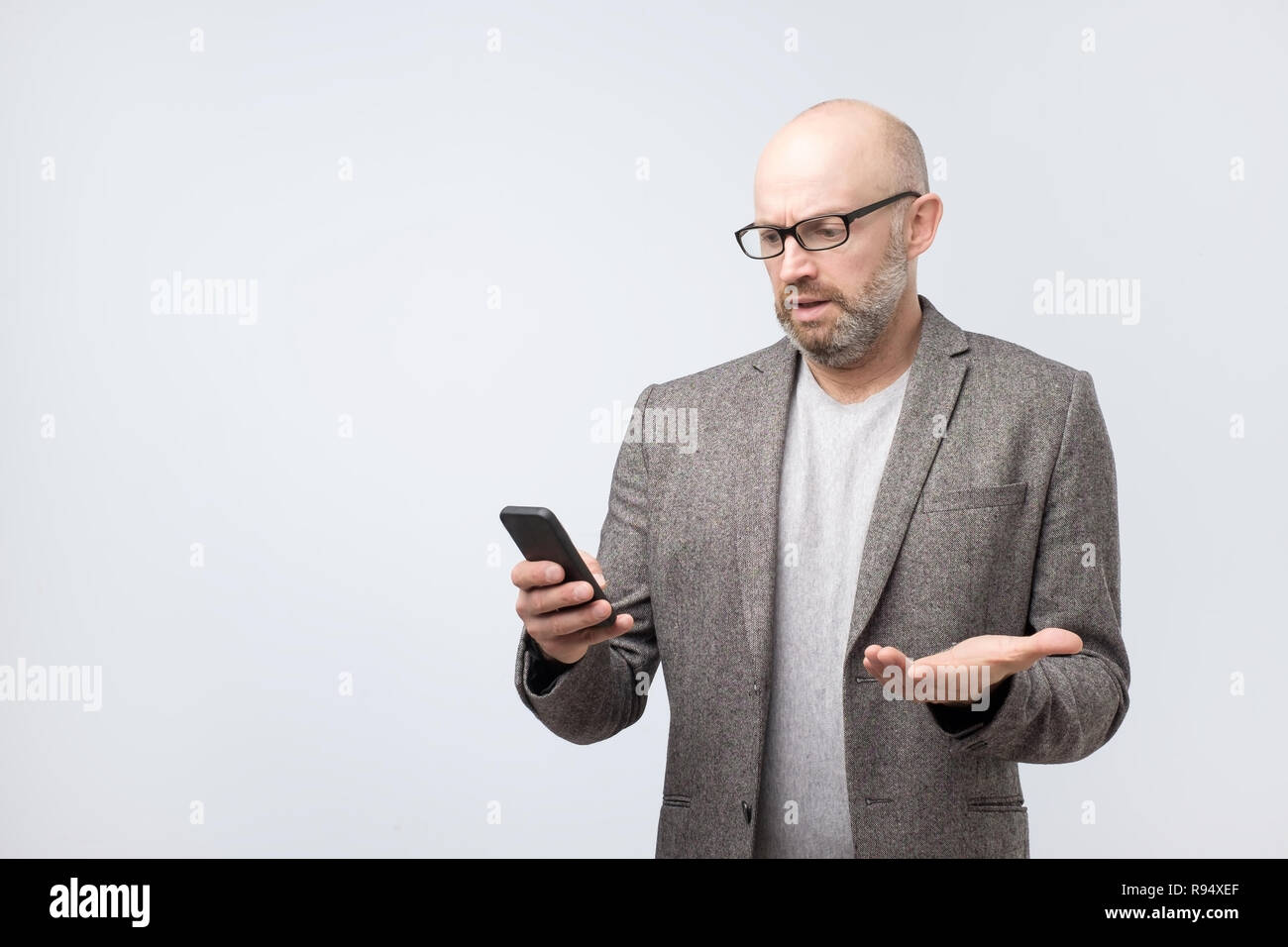 Perplesso uomo calvo lettura sms con faccia emozionale espressione Foto Stock