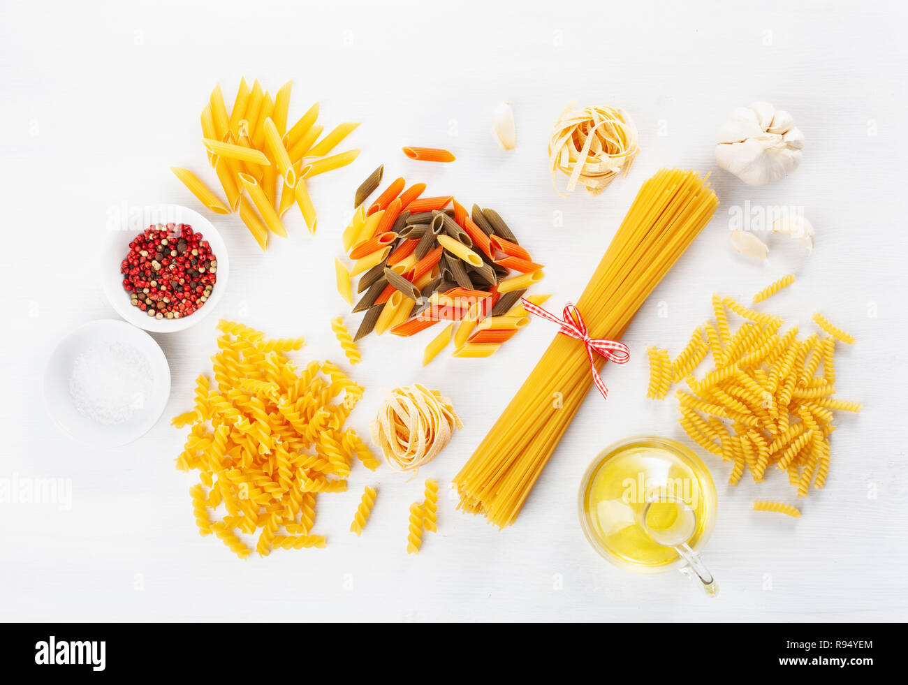 Un assortimento di pasta cruda laici piatta sul bianco. spaghetti fusilli penne tagliatelle girandole Foto Stock