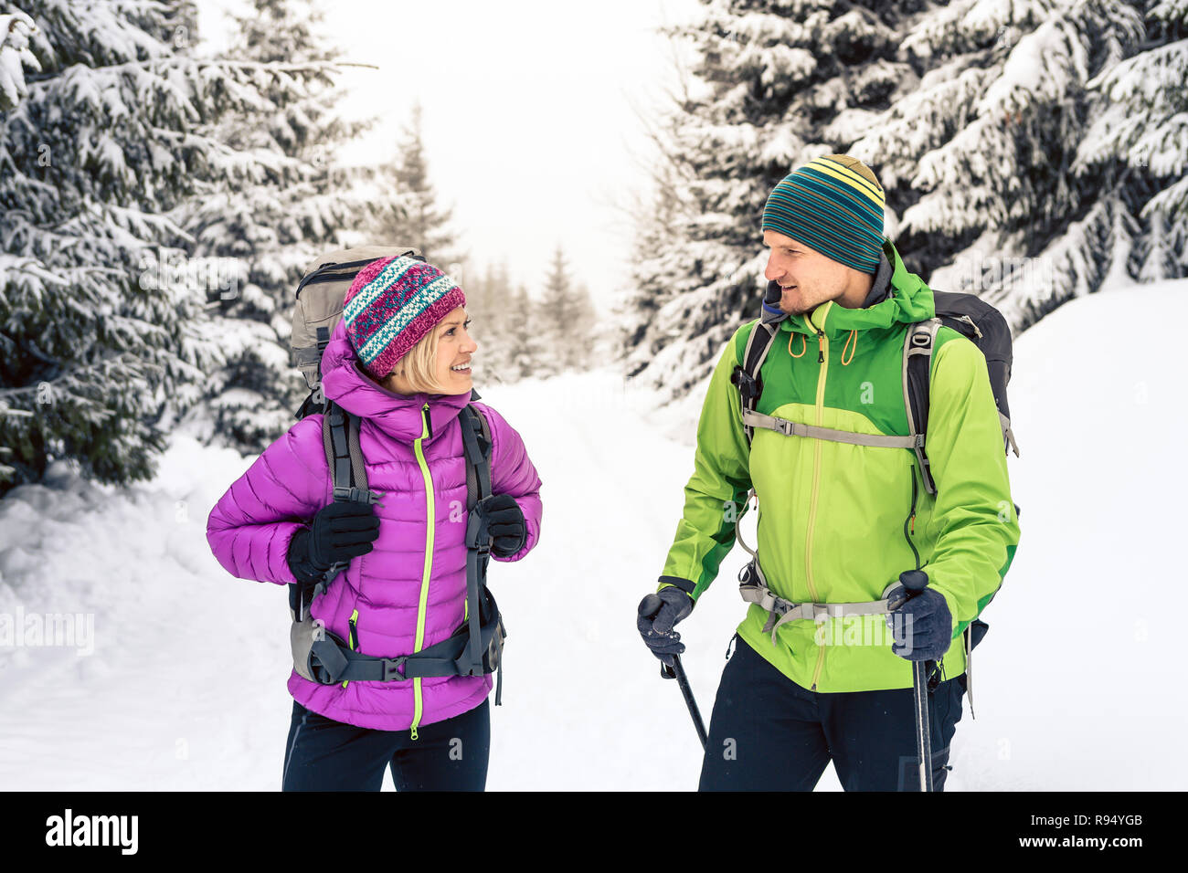 L uomo e la donna felice coppia escursionisti trekking in bianco inverno boschi e montagne. Giovani escursionismo team, la gente che camminava sul sentiero di neve con zaini, avvento Foto Stock