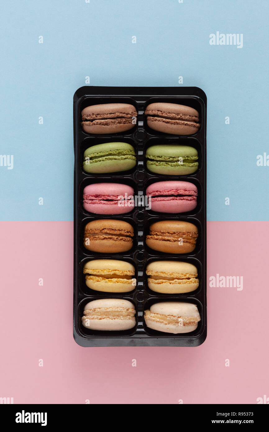 Colorati macarons francese nel pacchetto sul rosa-blu di sfondo - Immagine verticale Foto Stock
