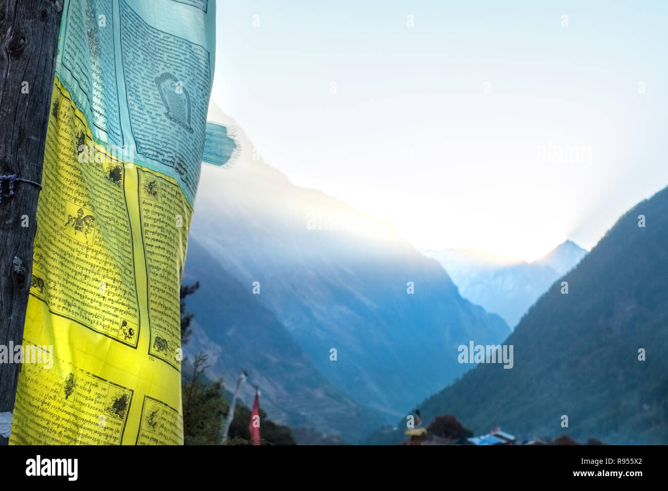 Alba nella regione di Manaslu del Nepal Himalaya con la luce del sole streaming su un crinale e bandiere di preghiera in primo piano Foto Stock