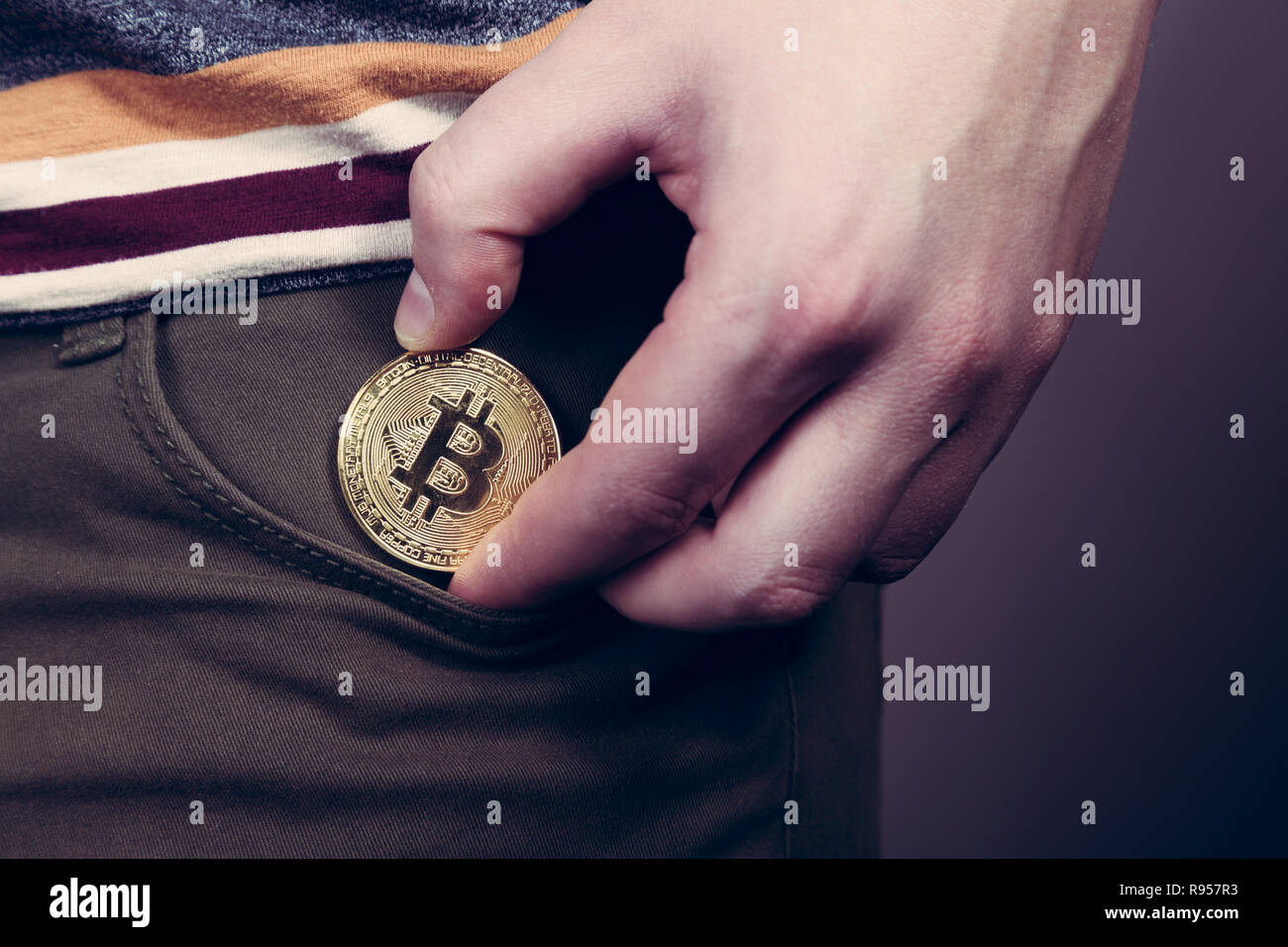 Mettere bitcoin cryptocurrency moneta nella tasca Foto Stock
