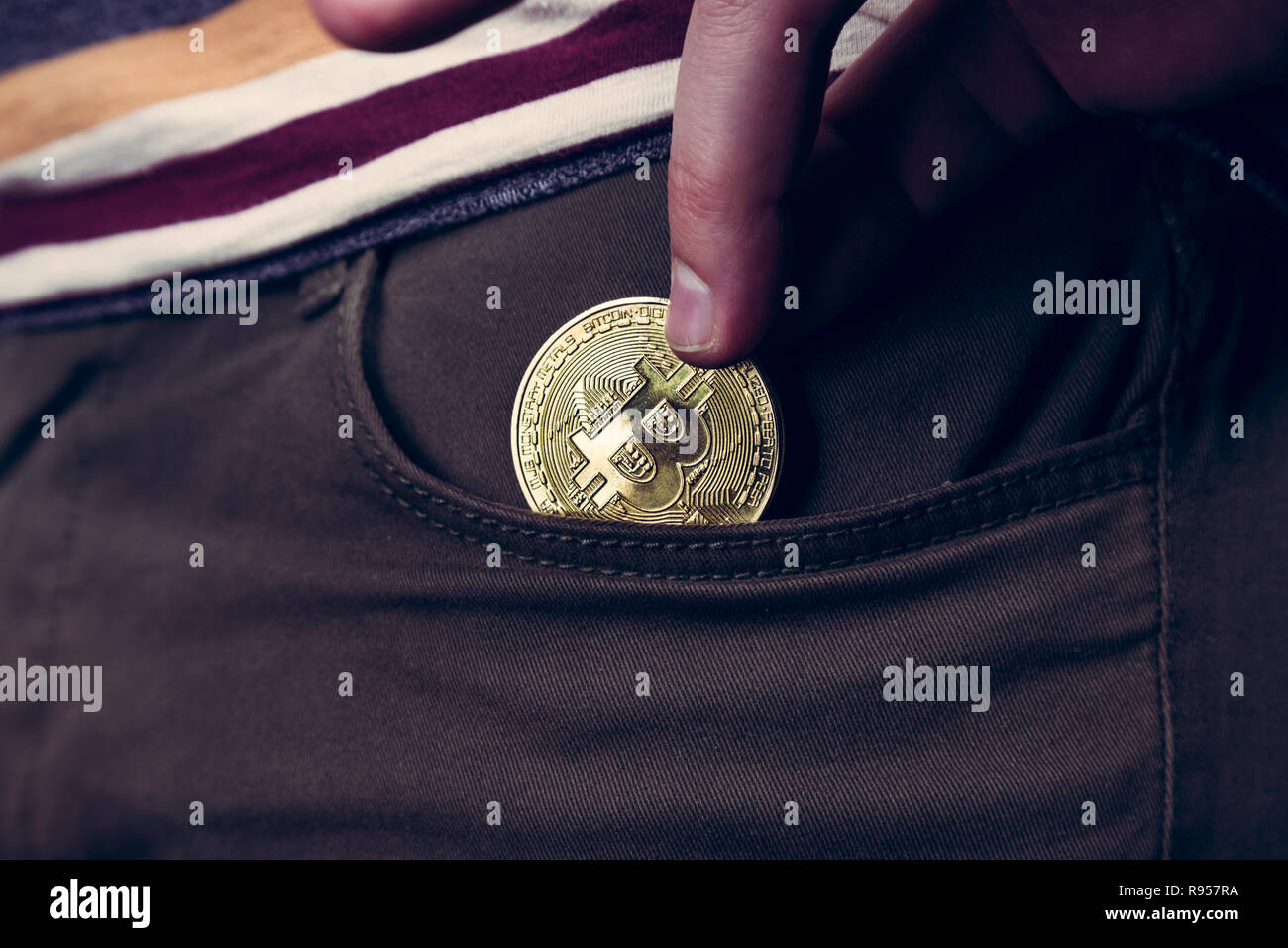 Mettere bitcoin cryptocurrency moneta nella tasca Foto Stock