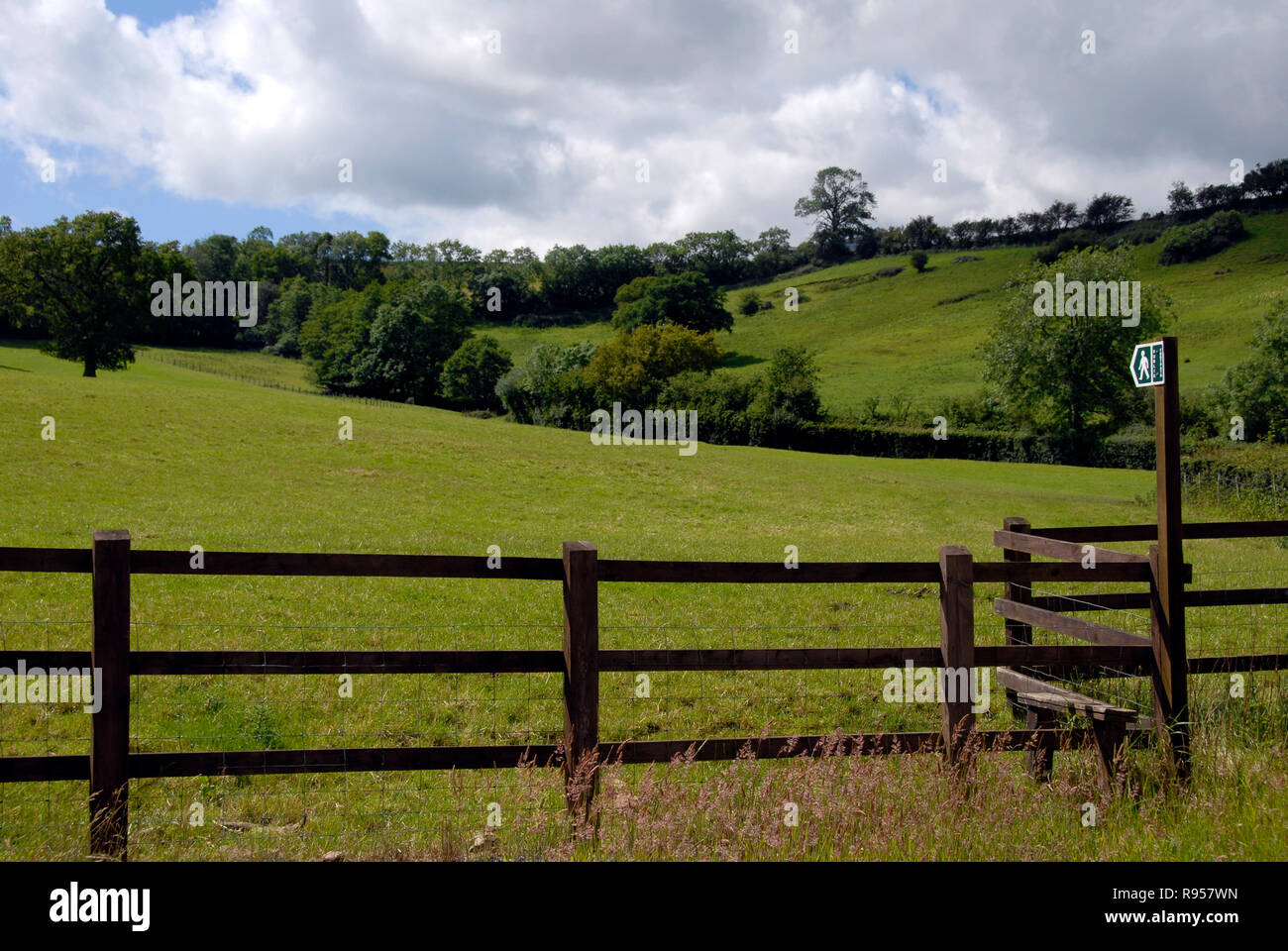 Staccionata in legno con stile dal cartello indicante sentiero pubblico nel campo Foto Stock