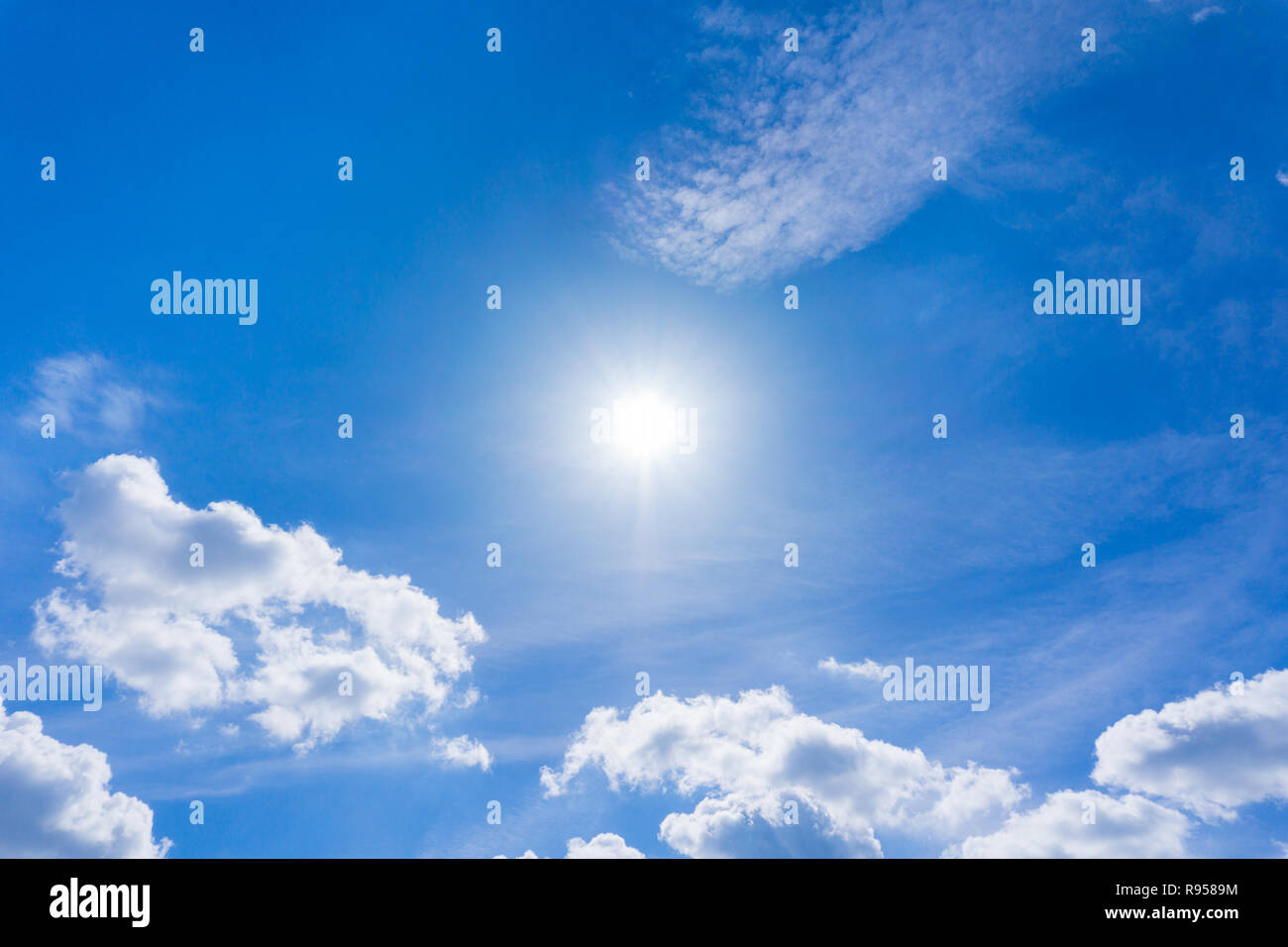 Bianchi e soffici nuvole e sole sul davanti del cielo blu. Foto Stock