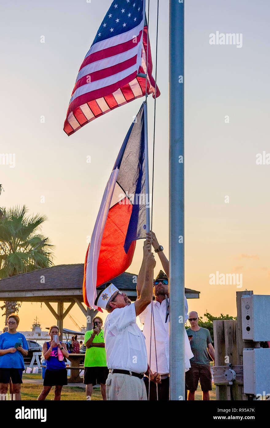 VFW Post membri abbassare la American e Texas bandiere al tramonto durante un uragano Harvey memoriale di servizio in Port Aransas, Texas. Foto Stock