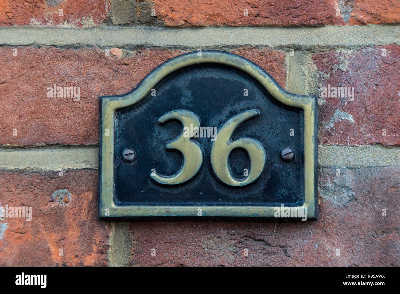 Il numero civico 36 in ottone su un rosso mattone a parete, Foto Stock