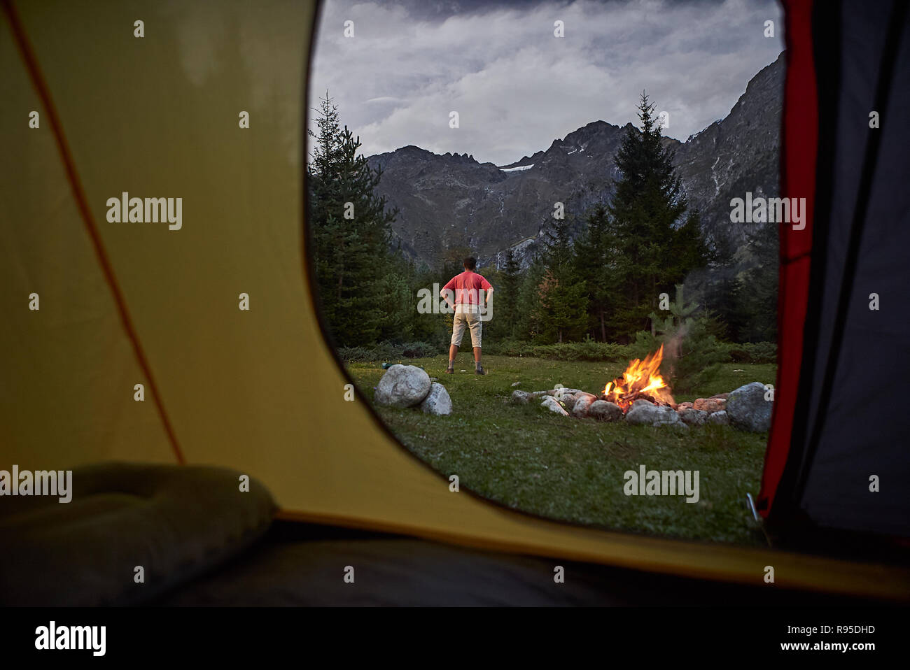 Vista dall'interno di tenda al tramonto. Da solo turista escursionista permanente al falò Foto Stock