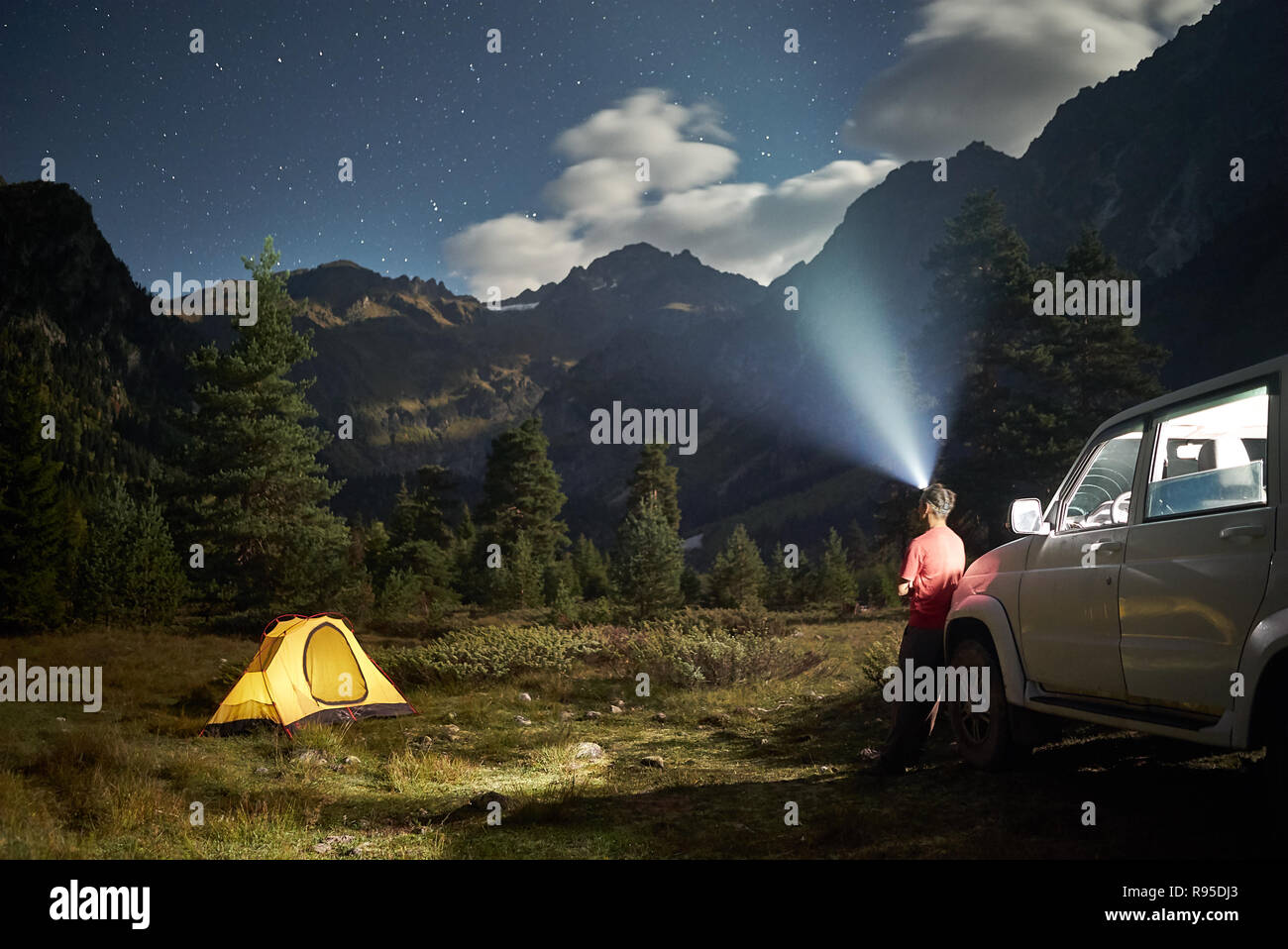 Camping con una vettura, giallo tenda a notte di luna, l uomo con faro a montagne Foto Stock