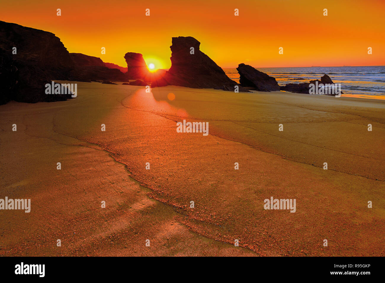 Scenic tramonto alla spiaggia rocciosa con marea di declino e mare calmo Foto Stock