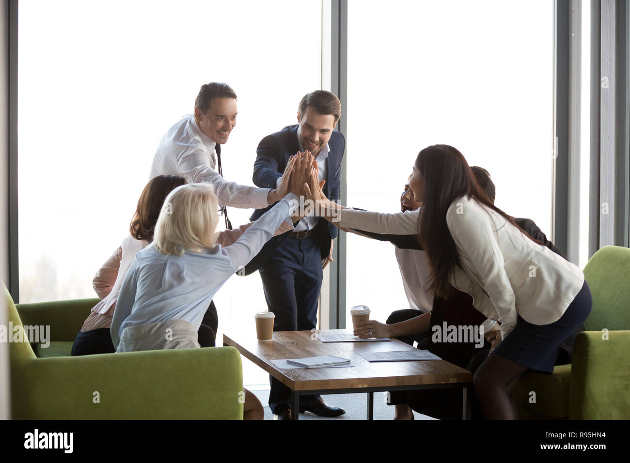 Multi-etnico imprenditori per celebrare il successo sul lavoro dando h Foto Stock