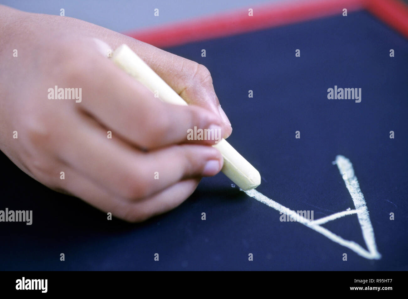 Bambino scrivere inglese alfabeto A su nero ardesia con Chalk Foto Stock