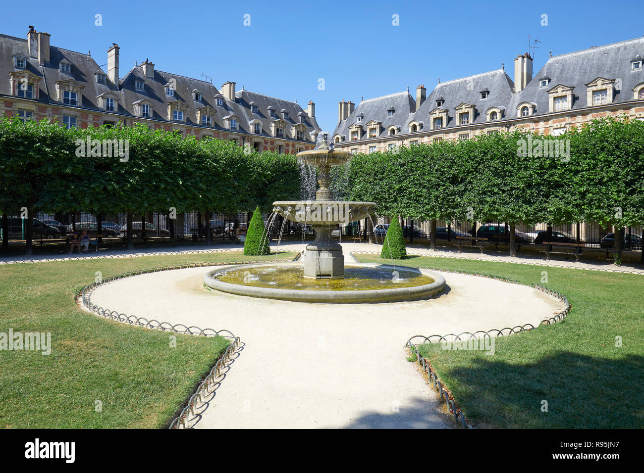 Place des Vosges con fontana a Parigi in una mattina di sole e cielo blu chiaro Foto Stock