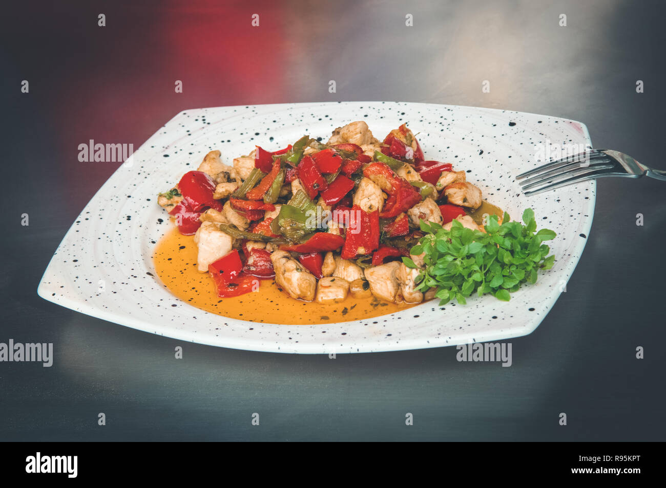 Pasto delizioso con arrosti di verdure e carne di pollo in pezzi piccoli in una piastra bianca. Foto Stock